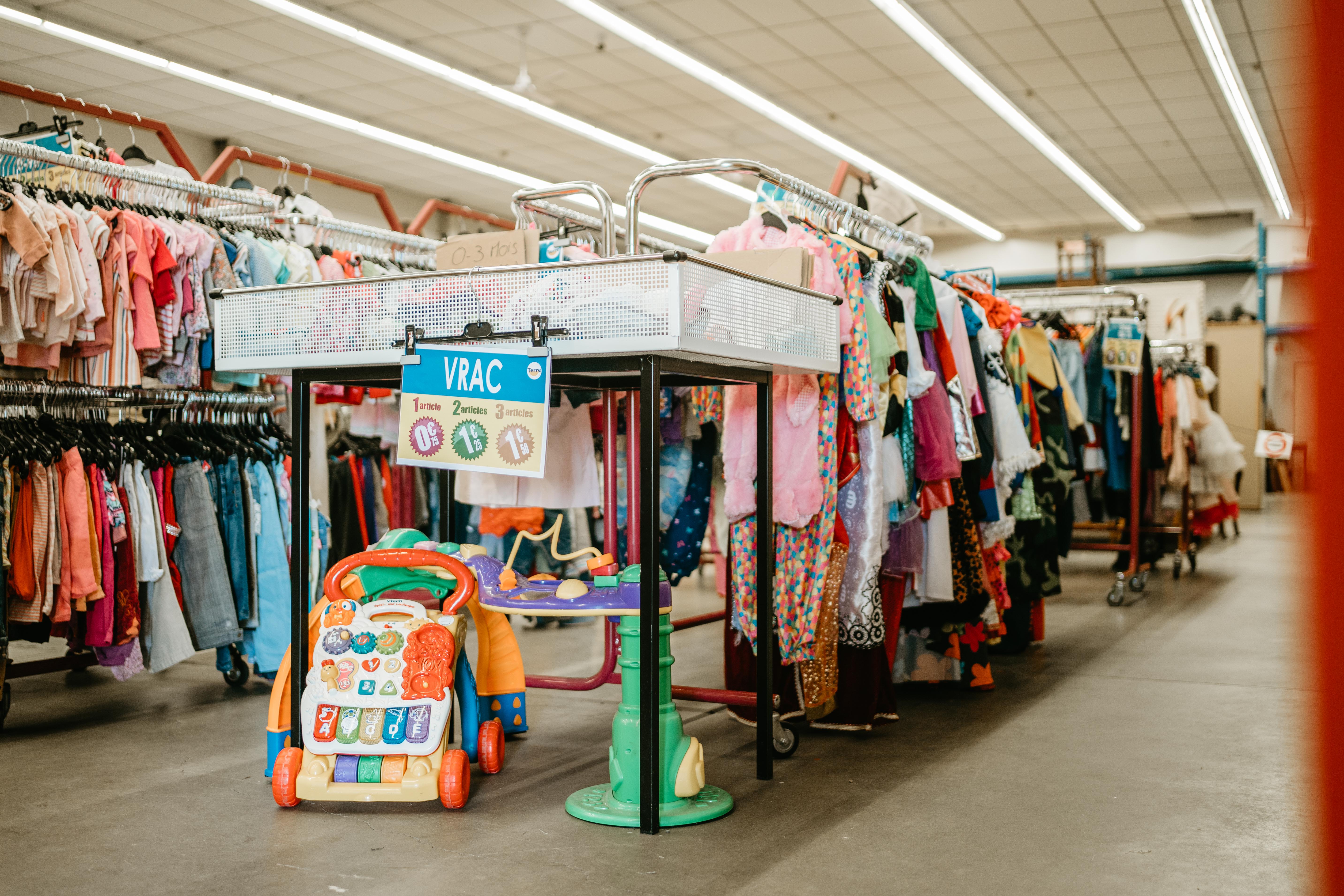 /Magasin%20pr%C3%A9sentant%20des%20v%C3%AAtements%20et%20des%20jouets%20expos%C3%A9s%20sur%20des%20%C3%A9tag%C3%A8res%2C%20offrant%20une%20vari%C3%A9t%C3%A9%20d%27articles%20pour%20enfants.