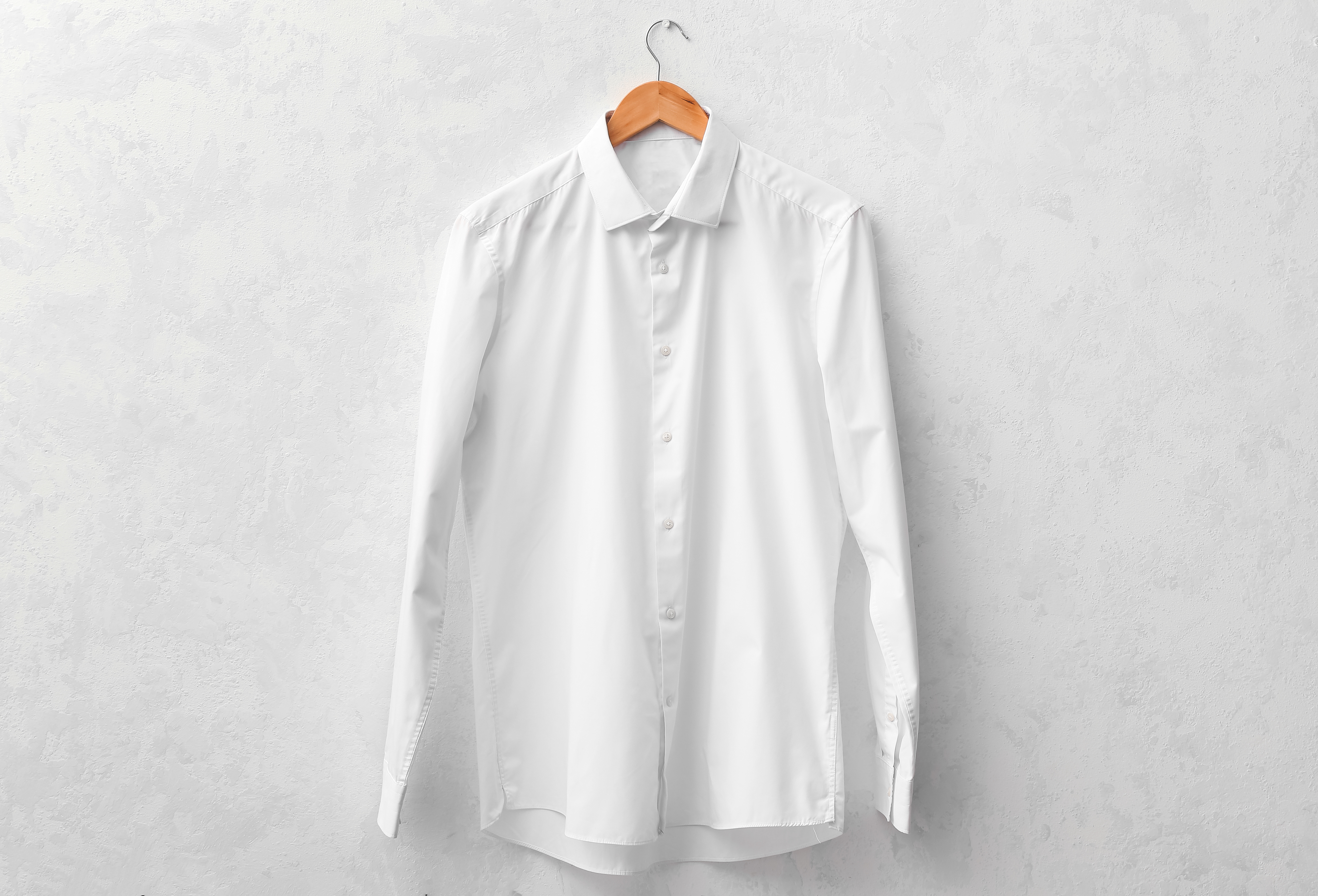 Chemise blanche accrochée sur un ceintre en bois
