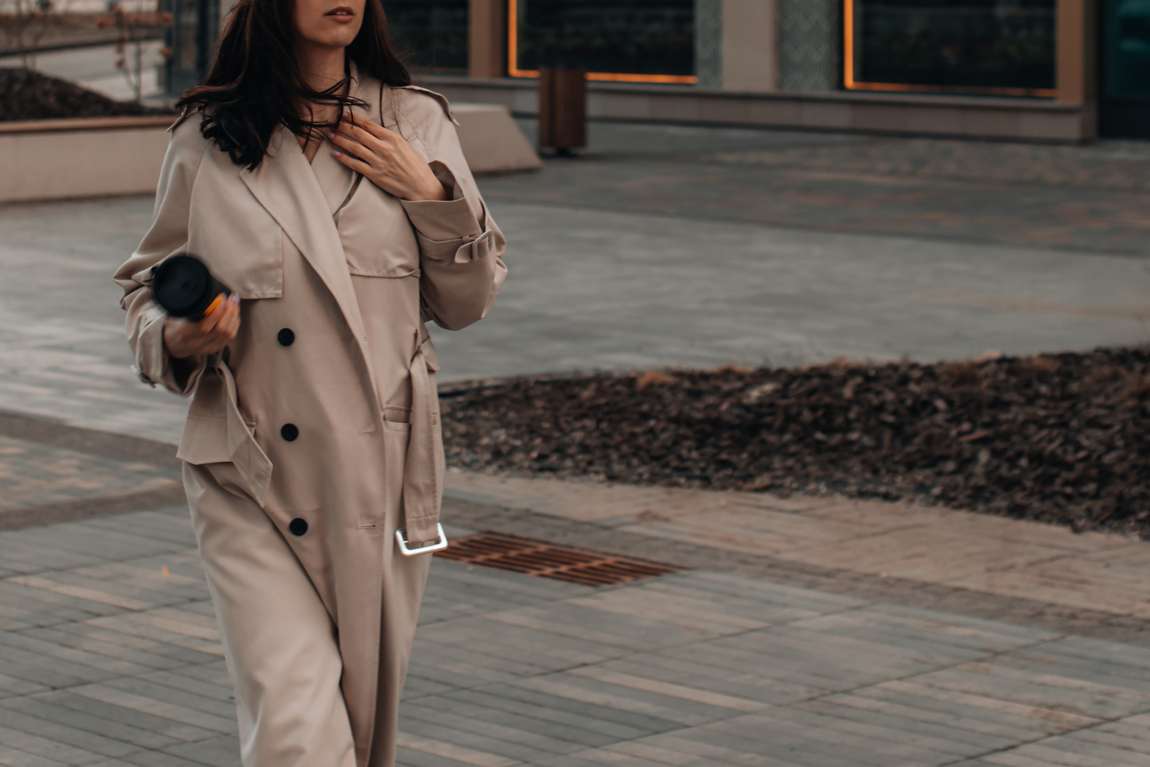 Une femme marche dans la rue avec un long trench beige