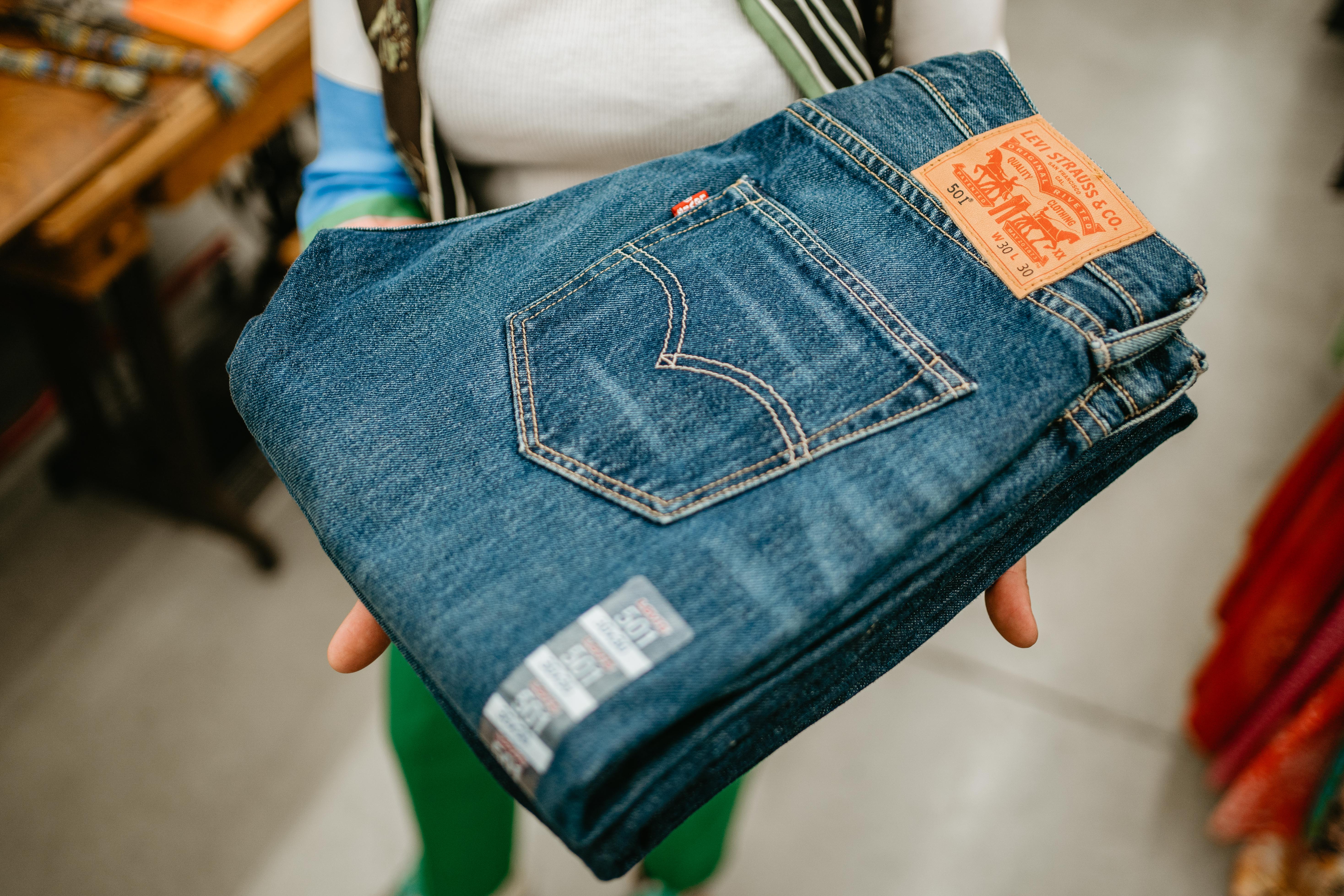 Une dame tient dans ses mains un jean neuf de la marque Levi's