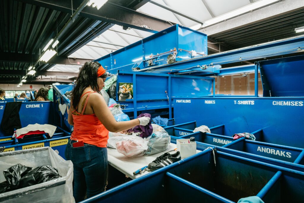 Une femme trie des vêtements dans un centre de tri textile