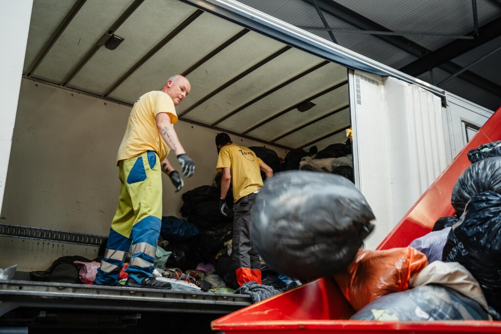 Des hommes jetent des sacs de vêtements hors du camion