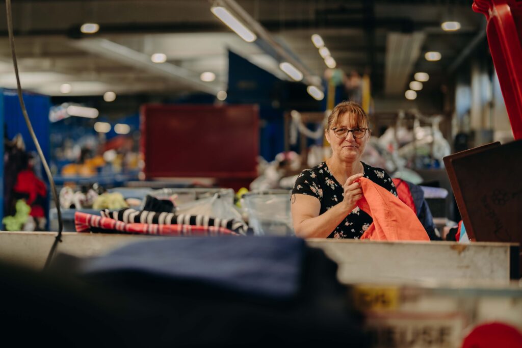 Une dame trie des vêtements dans un centre de tri Terre